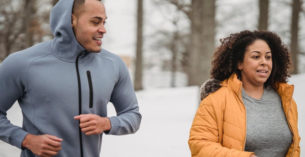 A trainer supporting woman during running workout in a park